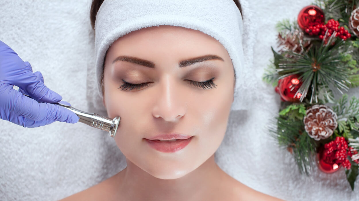 Woman receives aesthetic procedure while lying by holiday wreath