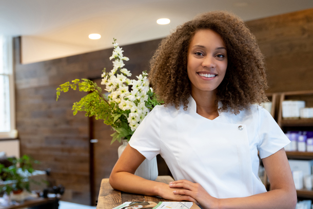 Aesthetician in medical spa lobby waiting to greet client with a smile