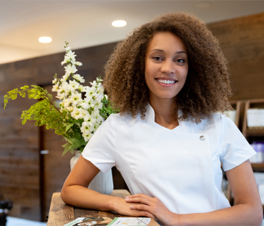 Aesthetician in medical spa lobby waiting to greet client with a smile