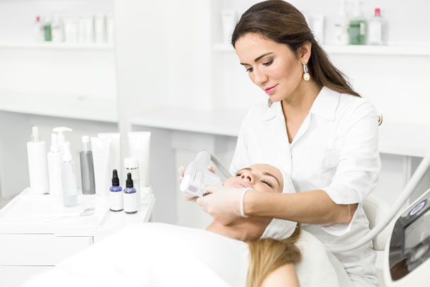 Medical Spa Practitioner with client in chair performing a medical spa treatment on her face