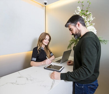 Receptionist writing on a tablet with a customer