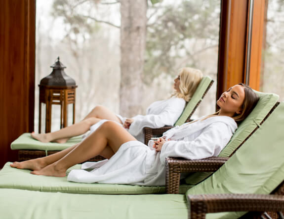 Two women relaxing on chairs in a spa environment.