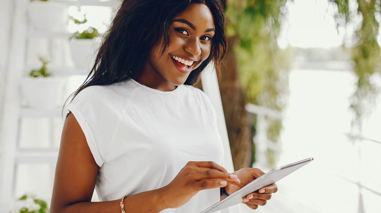 Aesthetician smiling and using spa software for small business on a tablet.