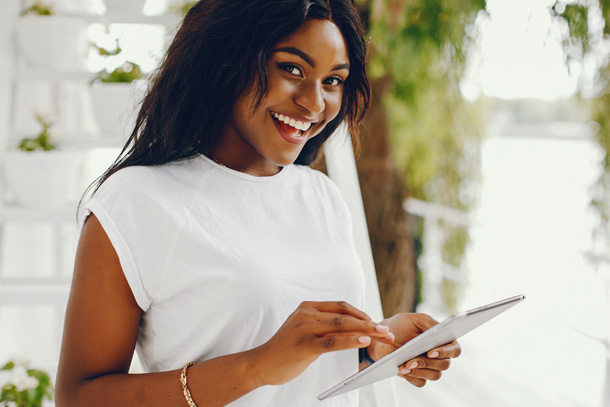 Aesthetician smiling and using spa software for small business on a tablet.