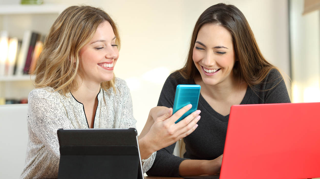 Two aesthetic industry professionals using multiple devices to look at the best medical spa software.