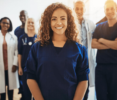 Smiling young female doctor standing in front of a team of medical aesthetics professionals.