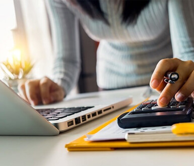 Person using a calculator and a laptop