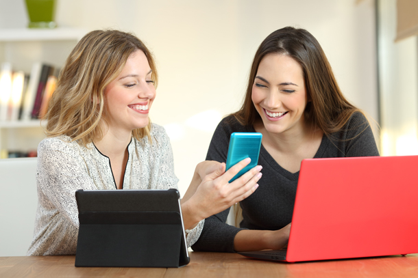 Two aesthetic industry professionals using multiple devices to look at the best medical spa software.