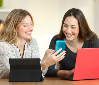 Two aesthetic industry professionals using multiple devices to look at the best medical spa software.