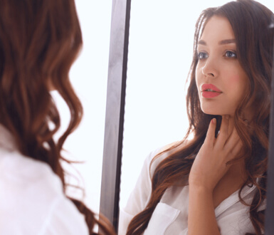 Young woman looking in a mirror at home.